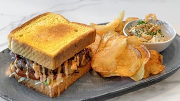 Un sandwich accompagné de frites et d’une petite portion de sauce, le tout servi sur une assiette.