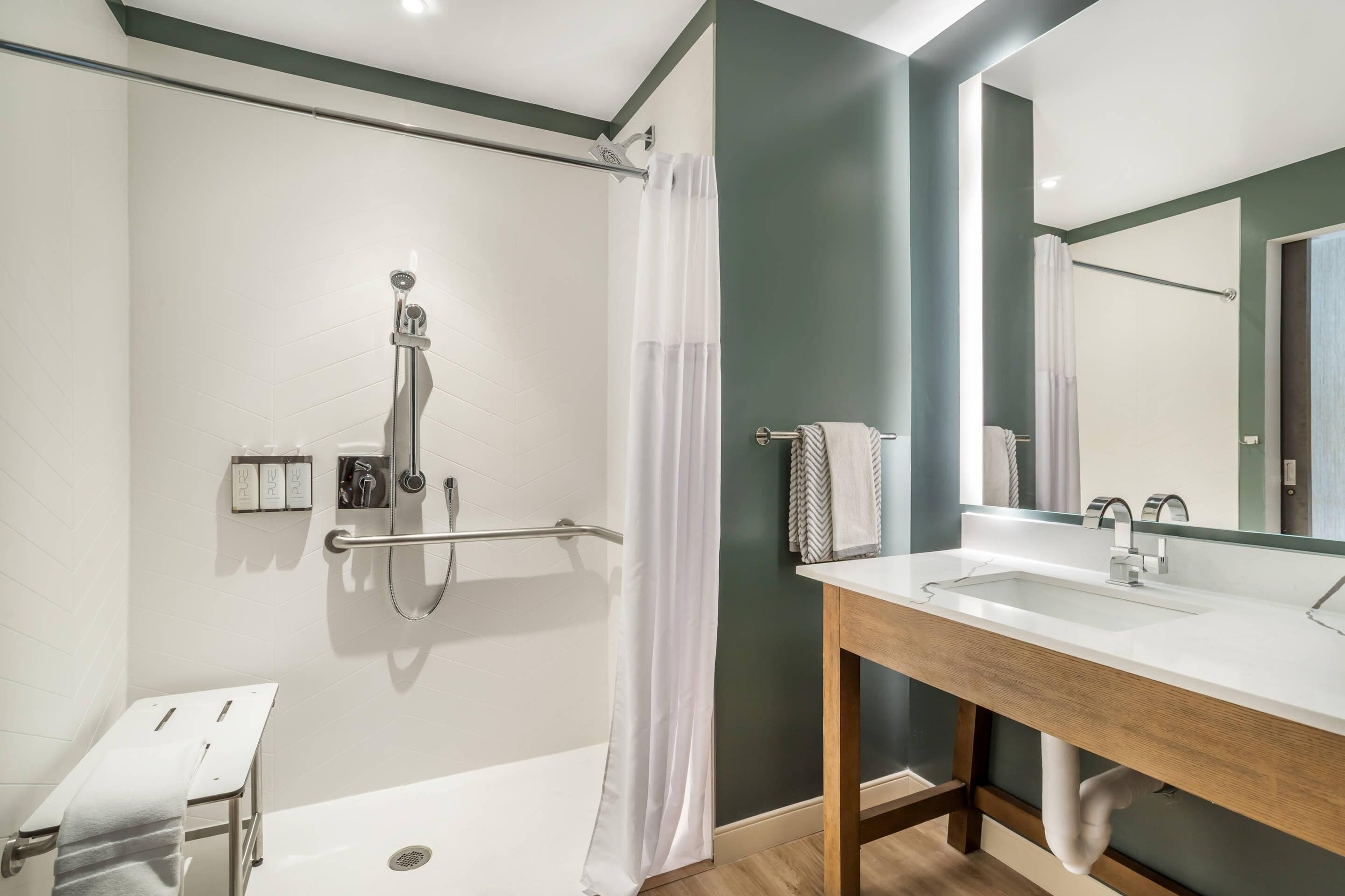 A modern bathroom with a shower, a bathtub, a vanity with a mirror, and a towel rack.