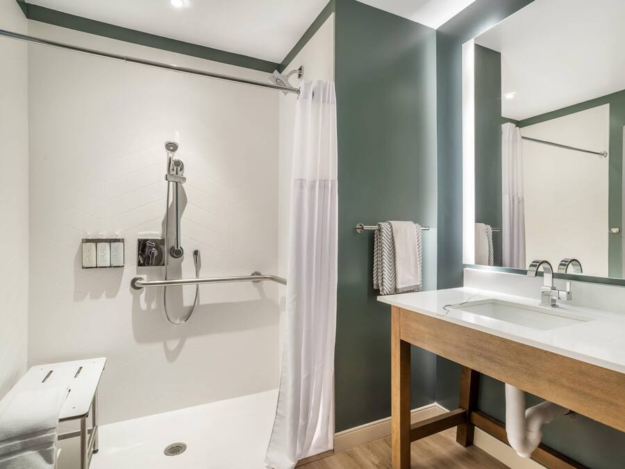 A modern bathroom with a shower, a bathtub, a vanity with a mirror, and a towel rack.