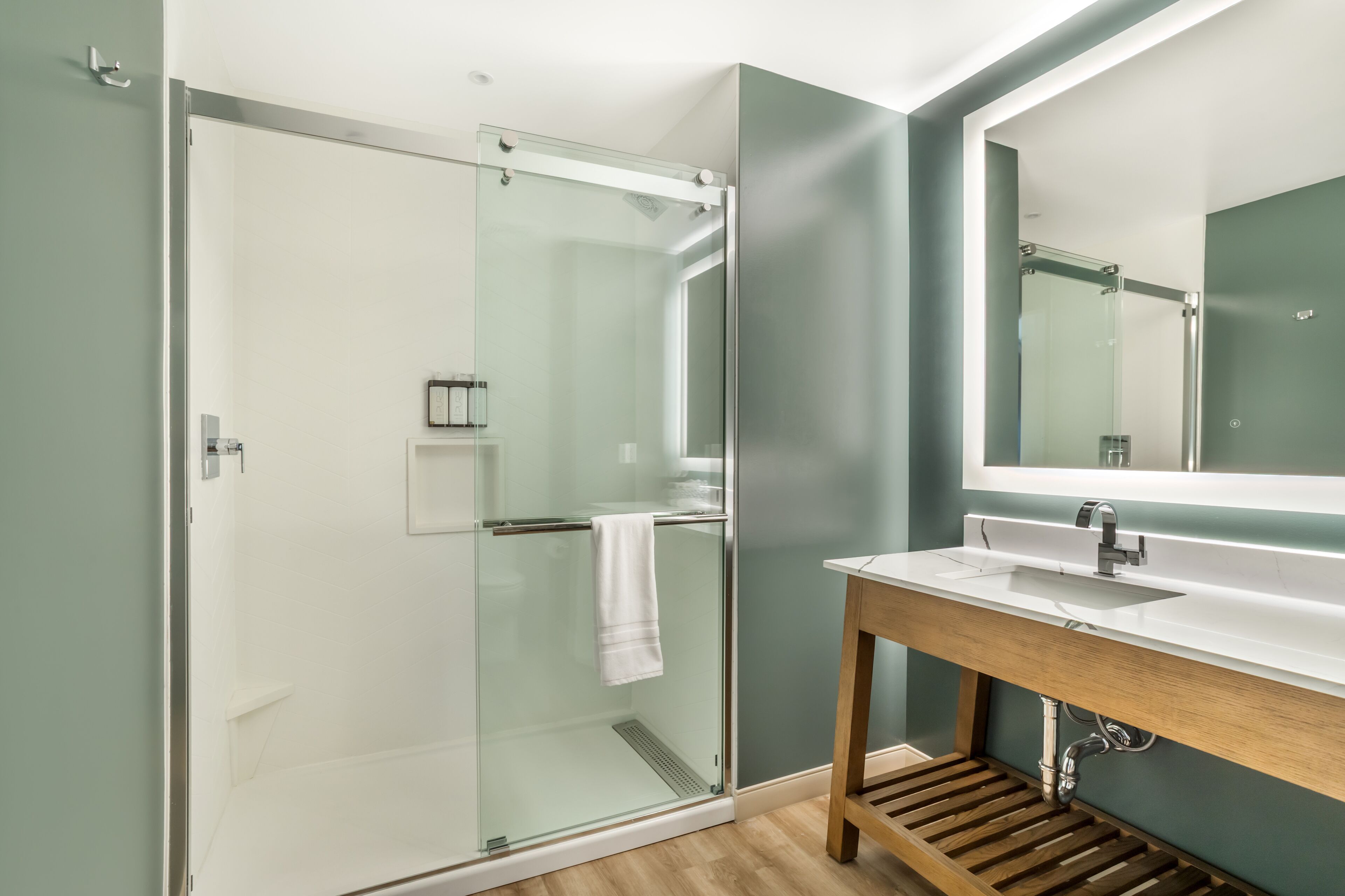 A modern bathroom with a glass shower enclosure, a wooden vanity, and a large mirror.