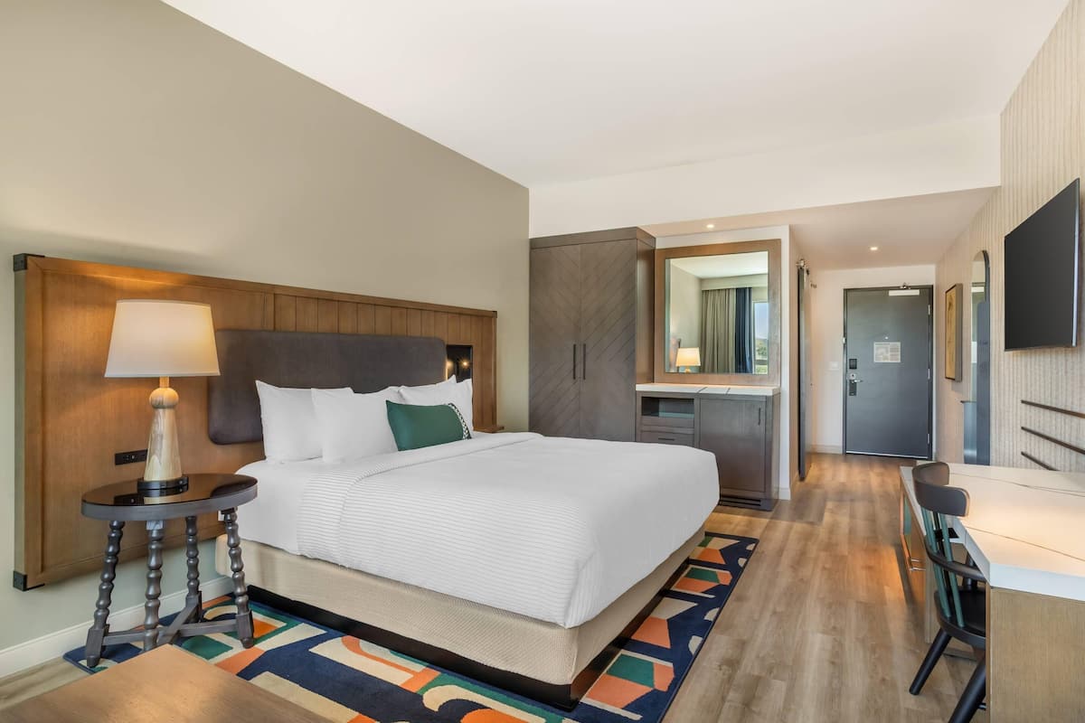 Une chambre d’hôtel avec un grand lit, une table de chevet, une lampe et vue sur la salle de bain.