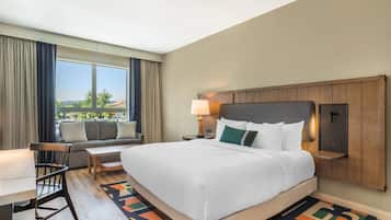 Habitación de hotel con una cama grande, un escritorio, una silla, un sofá y una ventana con vistas.