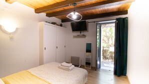 Ein Schlafzimmer mit einem Bett, einem Kleiderschrank, einem an der Wand befestigten Fernseher und einer Schiebetür zu einem Außenbereich.