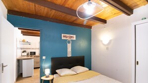 Ein Schlafzimmer mit Bett, Nachttisch und Blick auf eine Küchenzeile.