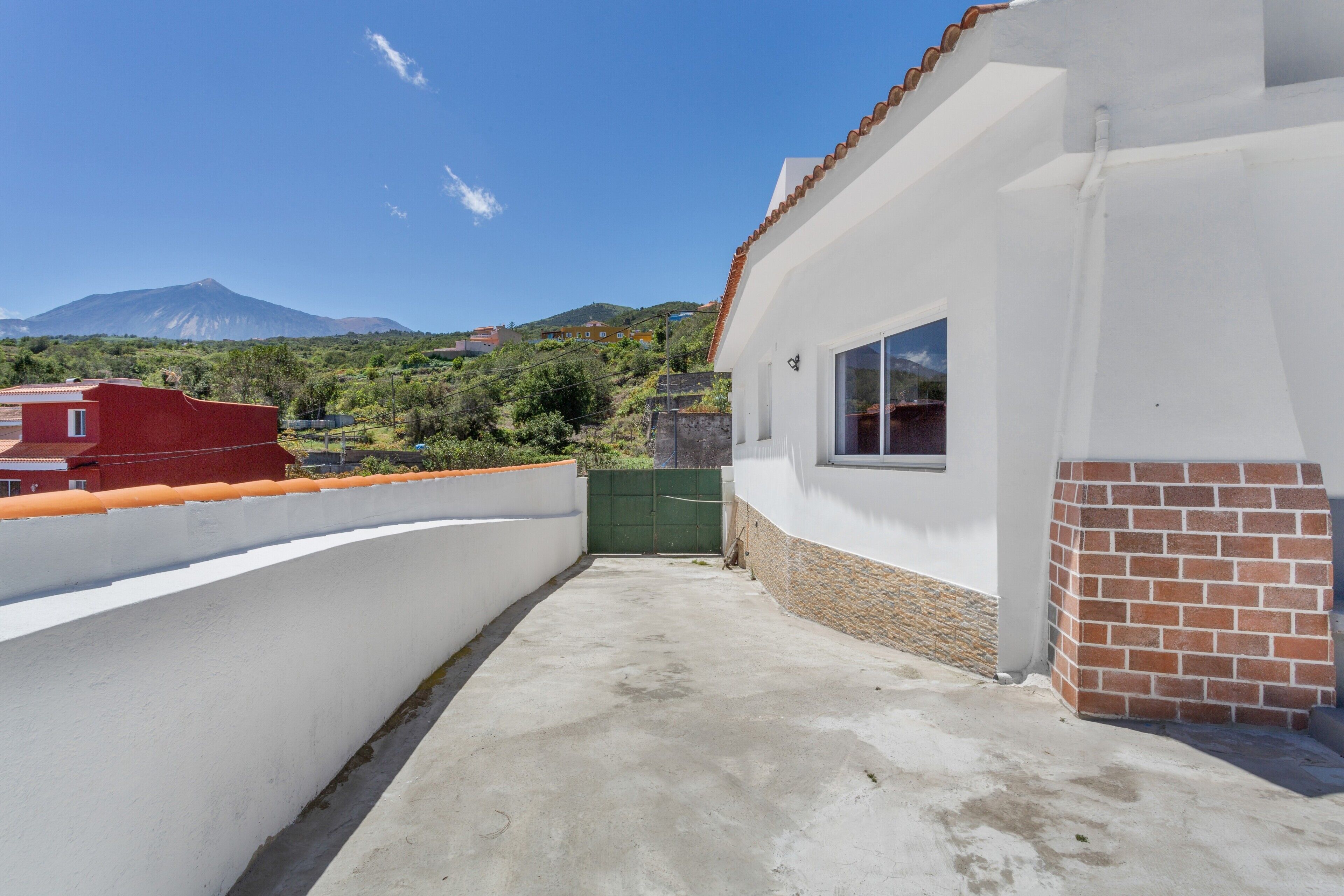 Un edificio con fachada blanca, una puerta verde y vistas a una montaña.