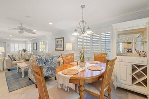 A dining area with a round wooden table, chairs, and a chandelier. There are white cabinets with glass doors and a ceiling fan. - Huge Villa! Sunroom, Pool, Near Crescent Beach! (Siesta Key)