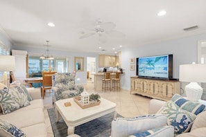 A spacious living room with a television, a dining area, and a kitchen.