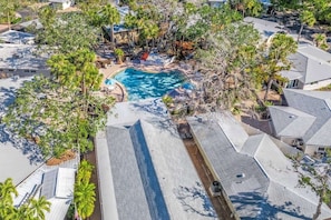 An aerial view of a residential area with a swimming pool surrounded by trees and houses.