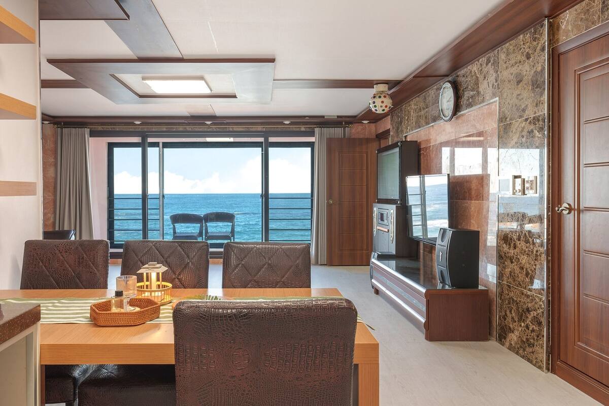Un coin repas avec vue sur la mer, une télévision et un meuble.