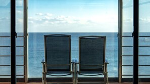 Twee stoelen gericht op een groot raam met uitzicht op de oceaan.