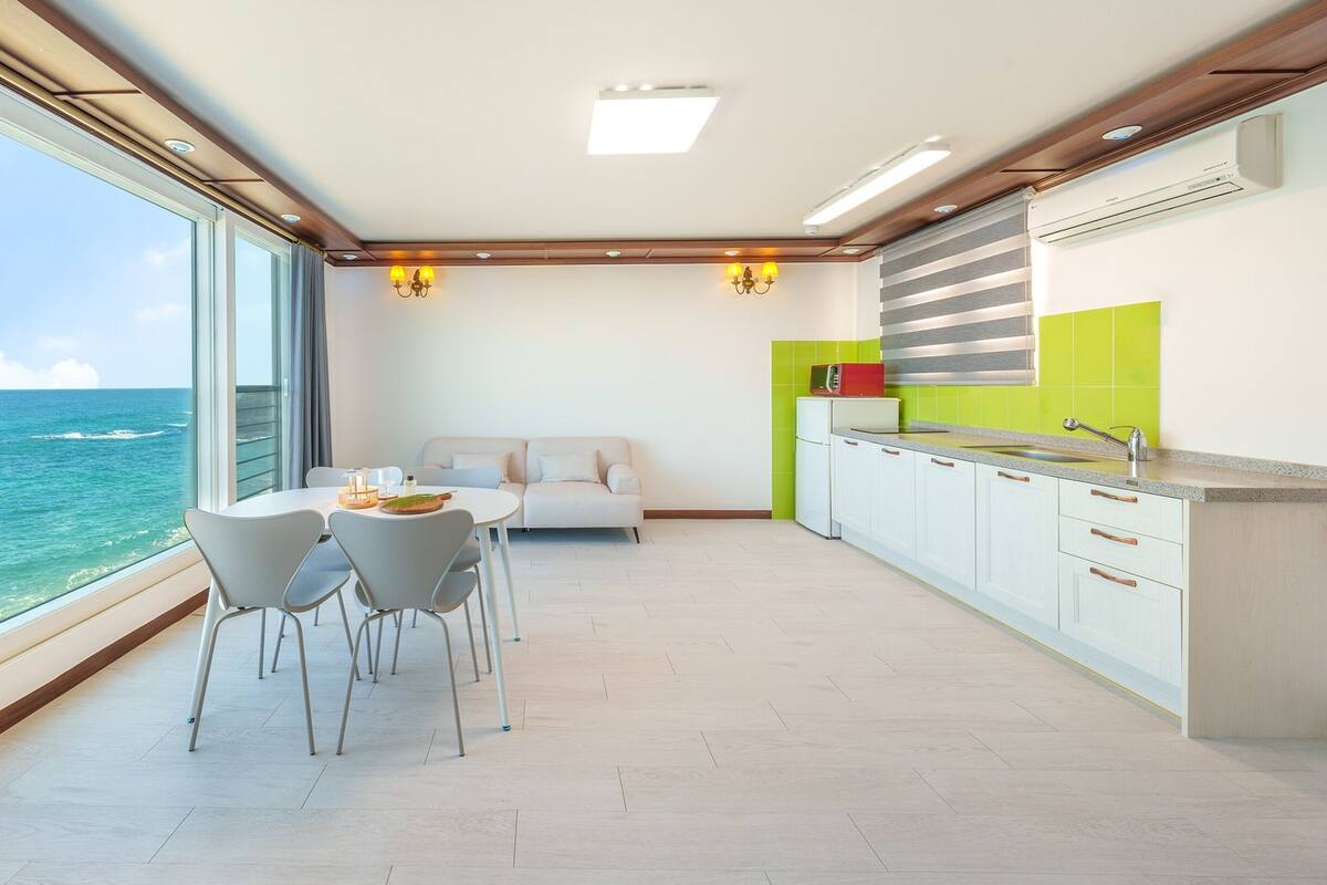 Une cuisine moderne avec vue sur l’océan, un coin repas avec une table et des chaises, et un espace de vie avec un canapé.