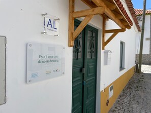 Ein Haus mit einem Schild, das es als regionale Unterkunft kennzeichnet, einer grünen Tür und einem kleinen Fenster.