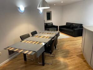 Ein moderner Essbereich mit einem langen Tisch, schwarzen Stühlen und einer schwarzen Ledersofa.