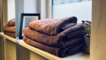 A shelf with folded towels and a potted plant.