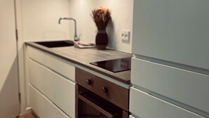 A modern kitchen with white cabinets, a wooden countertop, a built-in oven, and a vase with flowers on the counter. - Cozy Flats Silkeborg - S2 (Silkeborg)