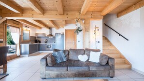 Un soggiorno moderno con soffitto in legno, un divano con cuscini, un tavolino da caffè e una scala.