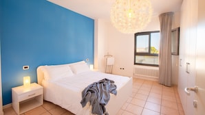 Une chambre à coucher avec un lit, une table de chevet et un luminaire suspendu.
