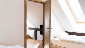 Een slaapkamer met een bed, een bank, een dakraam en een houten deur.