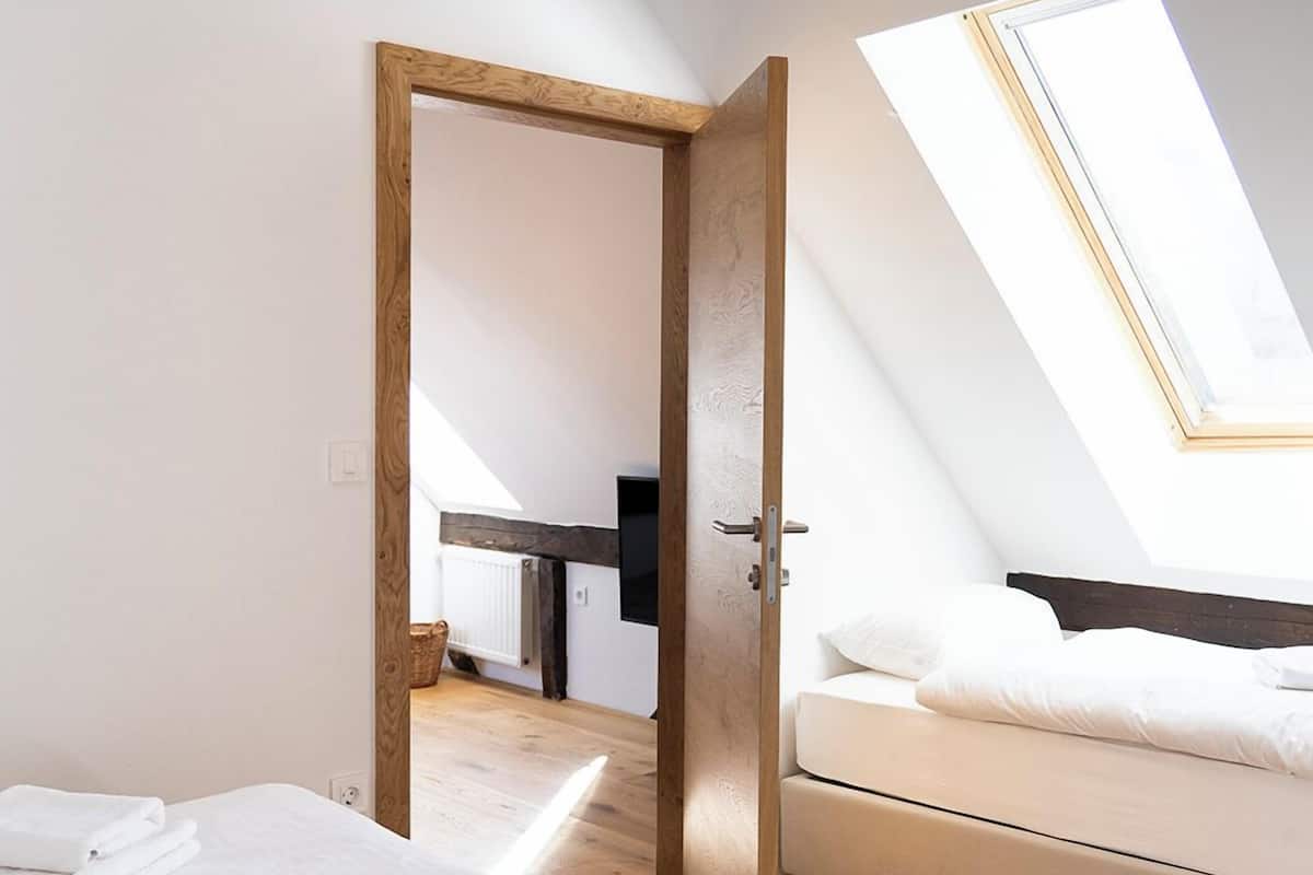 Un dormitorio con cama, sofá, tragaluz y puerta de madera.