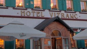 Hotel Vitranc, met een klassiek gevelontwerp, groene luiken en een bord dat het als hotel identificeert.
