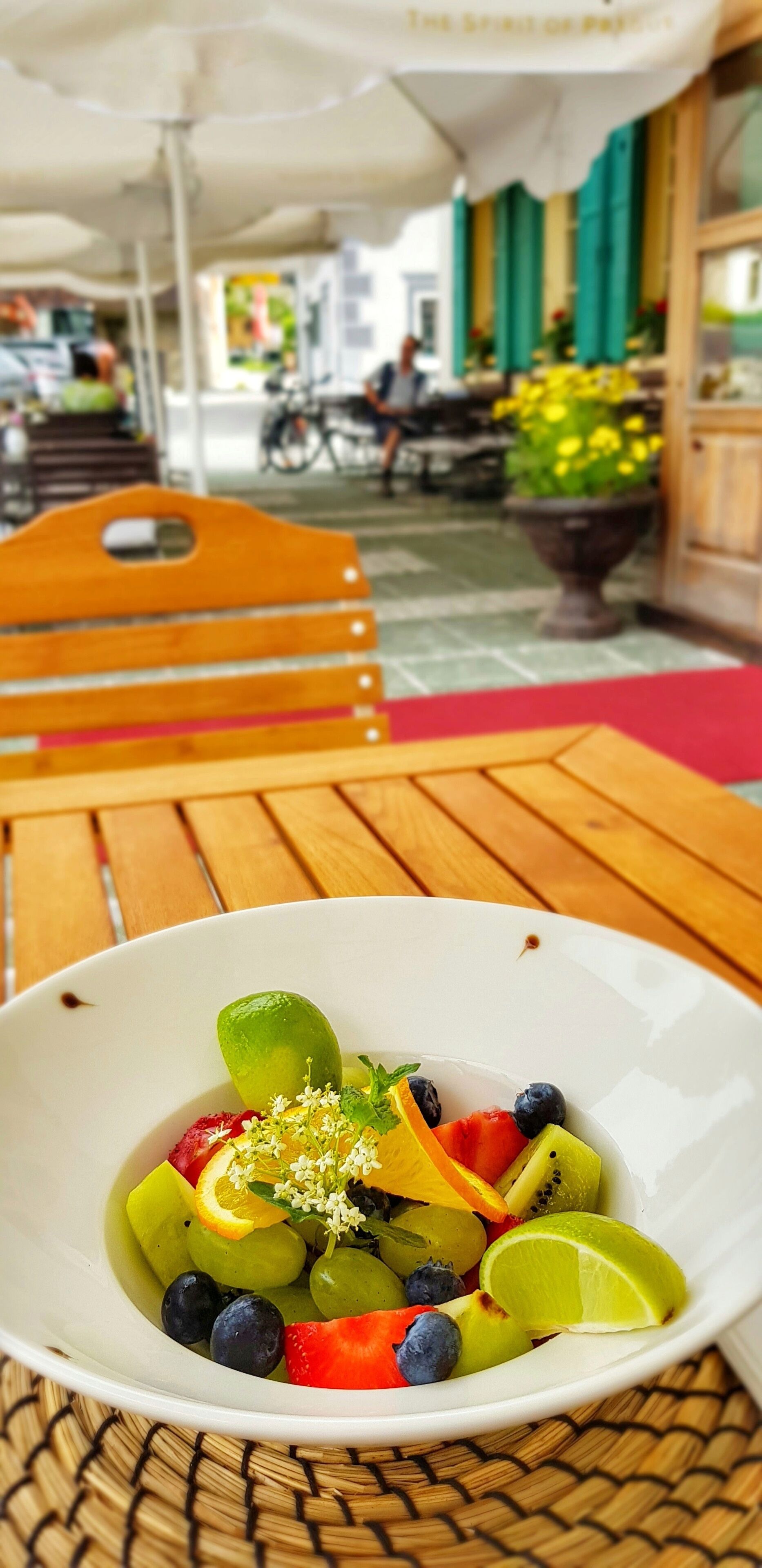 Eine Schale Obstsalat auf einem Holztisch, darunter eine rote Unterlage.