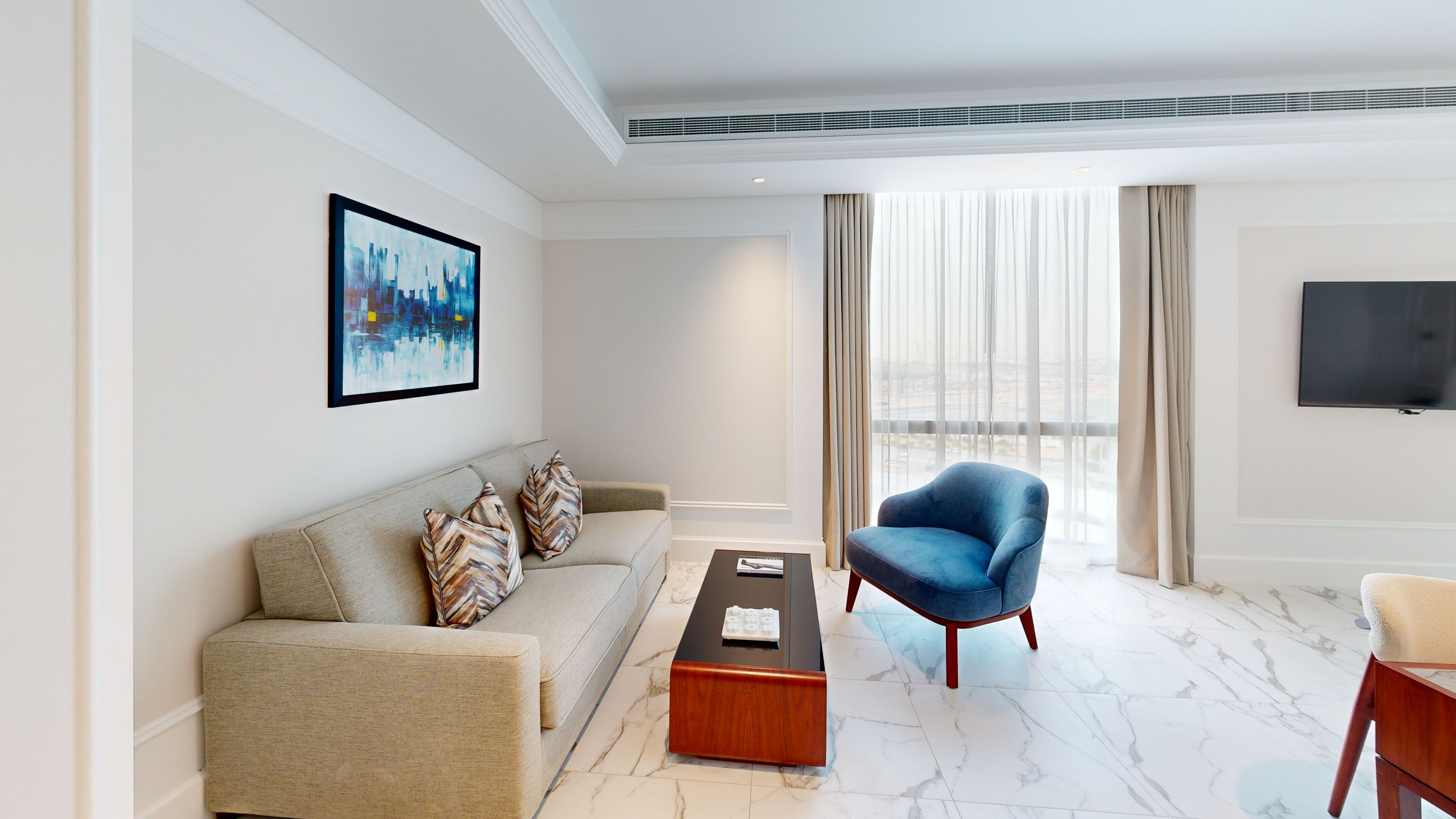 A modern living room with a sofa, a blue armchair, a coffee table, and a TV mounted on the wall.