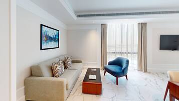 A modern living room with a sofa, a blue armchair, a coffee table, and a TV mounted on the wall.
