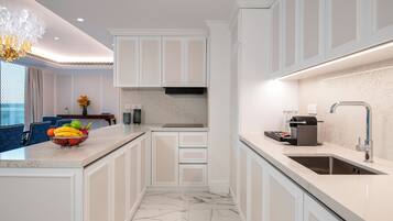 Una cocina moderna con armarios blancos, piso de mármol y una isla integrada con frutero.