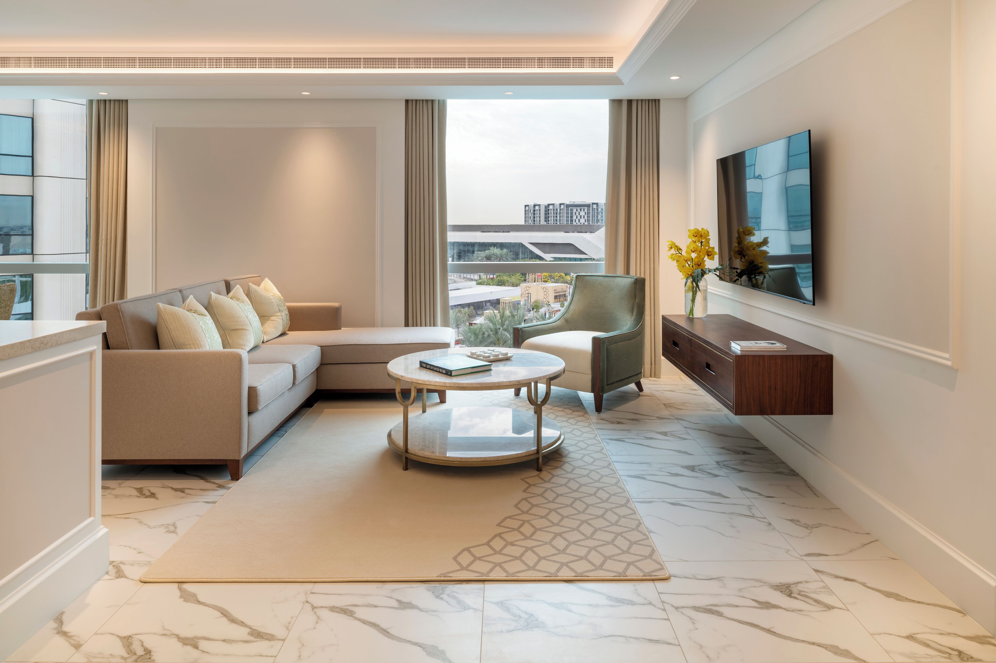 Een moderne woonkamer met een bank, fauteuil, salontafel en een wandgemonteerde flatscreen-televisie.