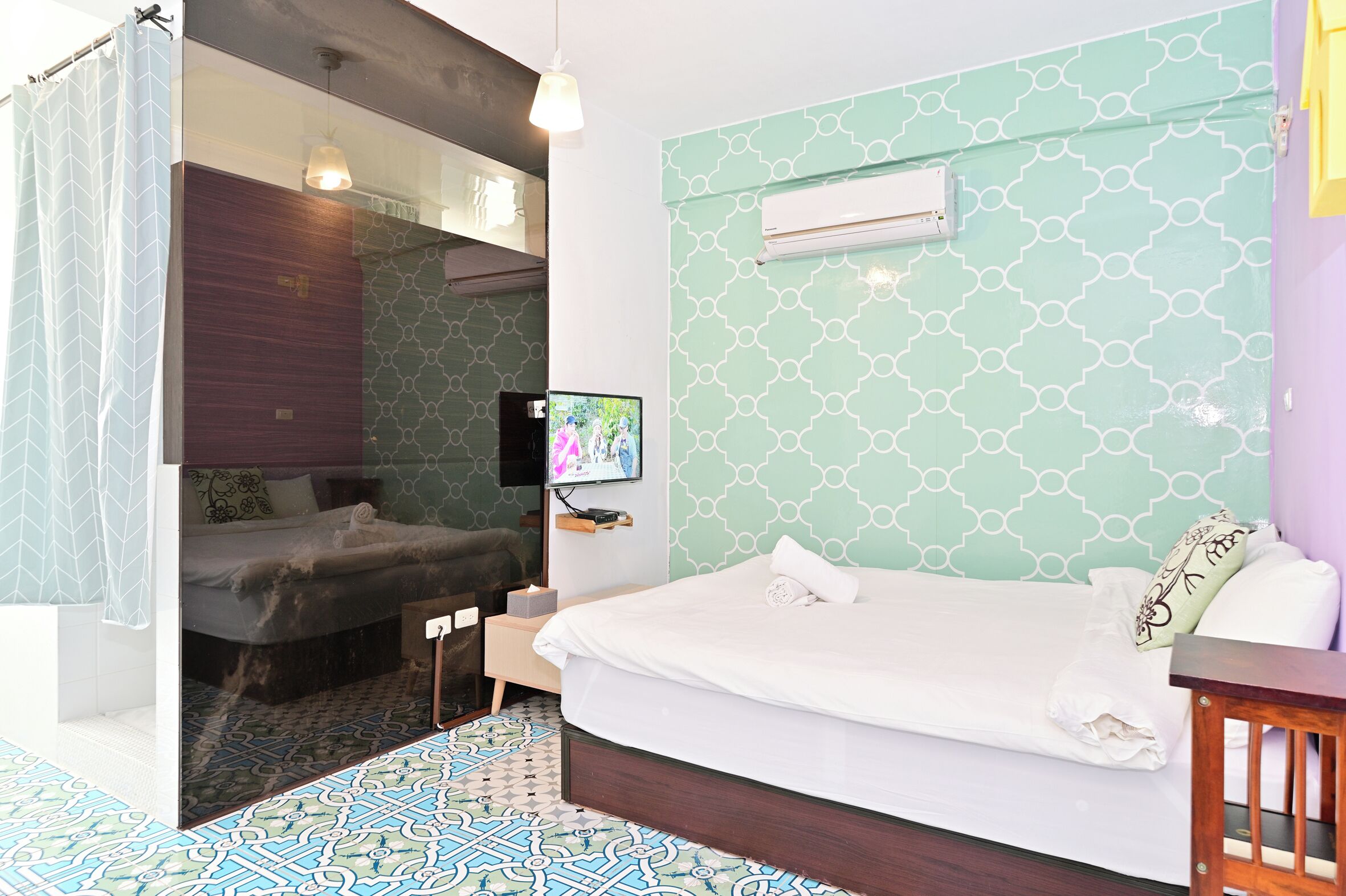A modern hotel room with a large bed, a TV, and a shower area.