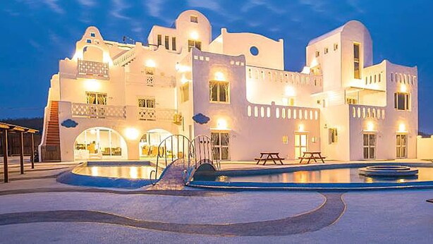 A large, white building with multiple balconies and a swimming pool. - Pescadores B&B (Magong)
