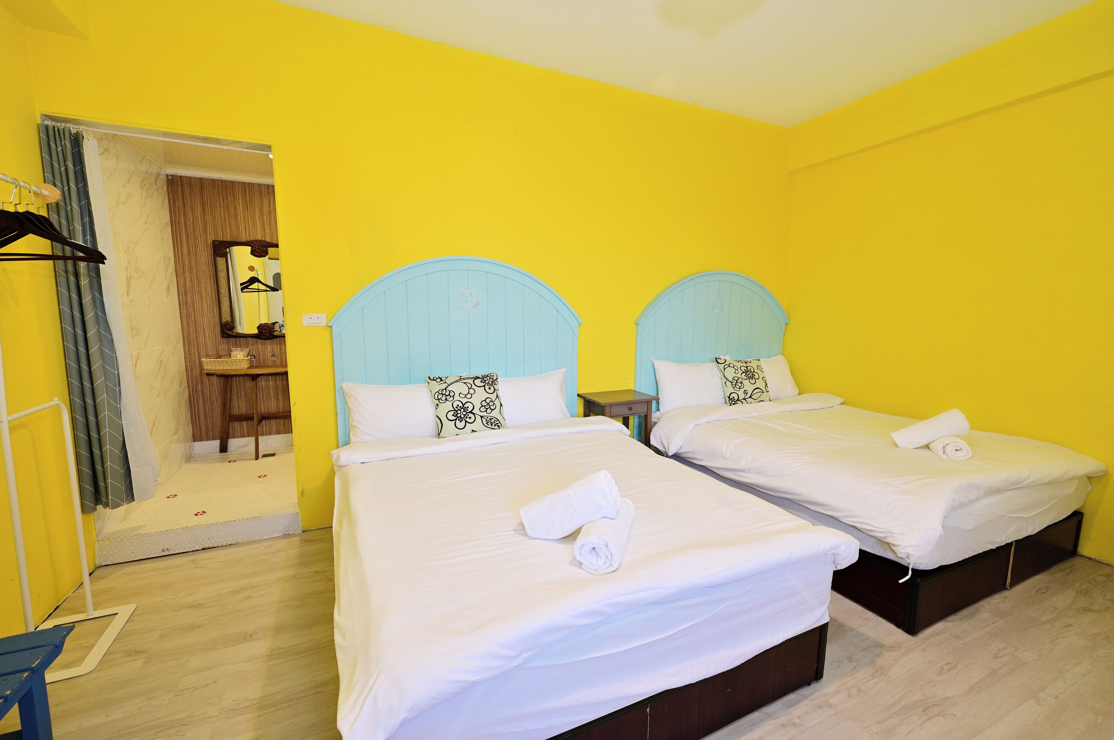A hotel room with two beds, a wooden floor, and a mirror on the wall.