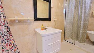 A bathroom with a white sink, a mirror, a shower curtain, and a toilet.