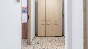 Un pasillo con un armario de madera, suelo de baldosas y una puerta que da a otra habitación.