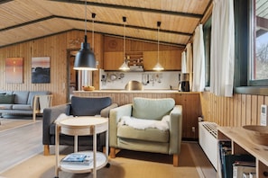 A cozy cabin interior with wooden walls, a dining area, a sofa, and a small table. - Cozy summer house in Trend (Løgstør)