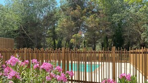 A wooden fence surrounding a swimming pool with pink flowers in the foreground. - Air-conditioned 3-bedroom villa with terrace, solarium and garden - V0767 (Vias)