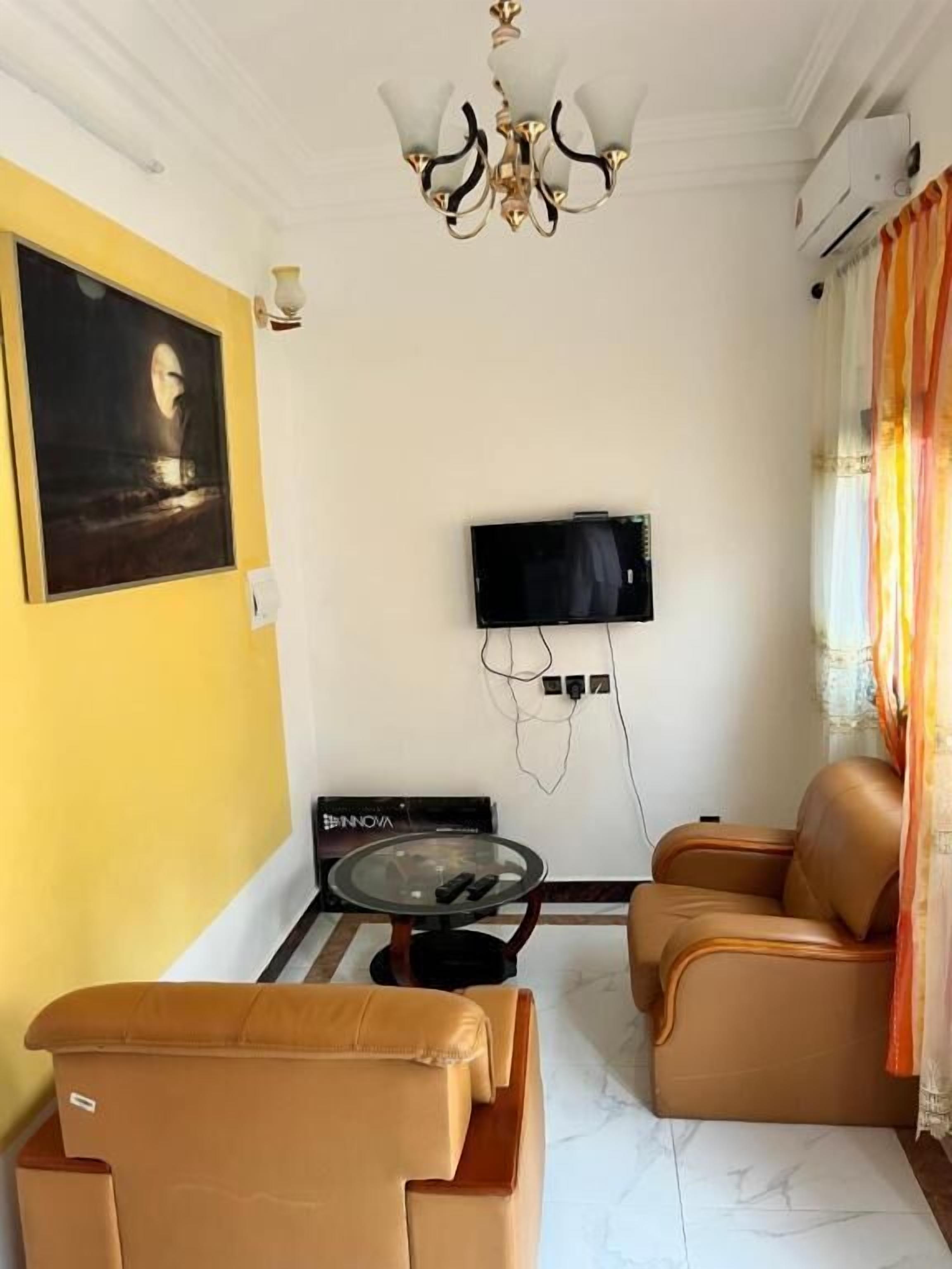 Un soggiorno con televisore, divano e tavolo.