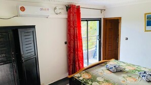 A bedroom with a bed, a wardrobe, a window with red curtains, and a door leading outside. - Prestige Beach Residence (Kribi)