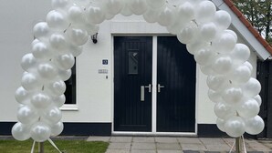 A white building with a black door and a number plate reading "12 POLMAN". - Topsleep Villa Lathum (Watervogel 12, 6988 CB LATHUM)