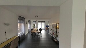 A modern kitchen with a dining area, a small Christmas tree, and a TV in the background. - Topsleep Villa Lathum (Watervogel 12, 6988 CB LATHUM)