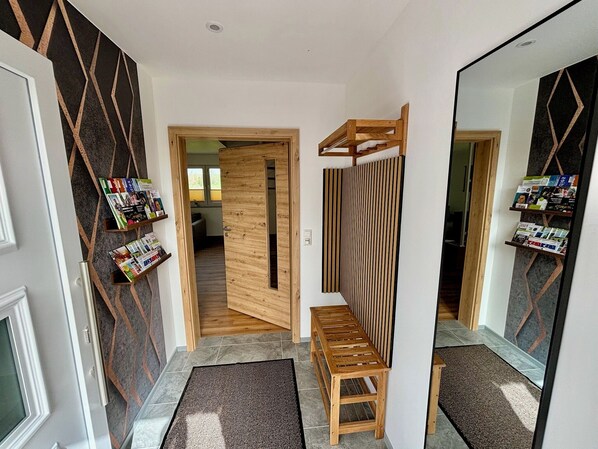 A hallway with a wooden bench, a mirror, and magazines on a shelf. - A comfortable, barrier-free vacation home in a quiet location with high-end amenities (Kronach)