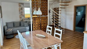 A modern living space with a dining area, a grey sofa, a staircase, and a wooden floor. - Comfortable, barrier-free vacation home in a quiet location with top facilities  (Kronach)