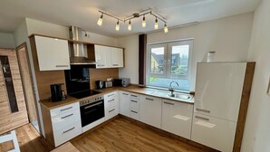 A modern kitchen with white cabinets, a built-in oven, a sink, and a window providing natural light. - Comfortable, barrier-free vacation home in a quiet location with top facilities  (Kronach)