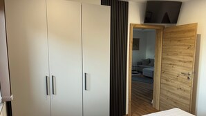 A bedroom with a bed, a wardrobe, and a wooden door leading to a living area. - Comfortable, barrier-free vacation home in a quiet location with top facilities  (Kronach)