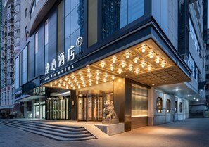 A hotel entrance with a modern design, featuring a prominent entrance, a statue, and a well-lit facade. - Manxin Hotel Wuhan Hankou Xinhua Road (Wuhan)