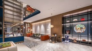 En moderne hotellobby med reception, siddeområde og et stort digitalt skærm.