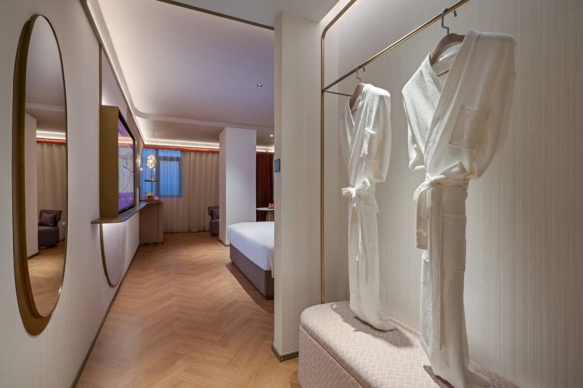 Ett hotellrum med en stor spegel, en säng, en sittgrupp och en klädhängare.