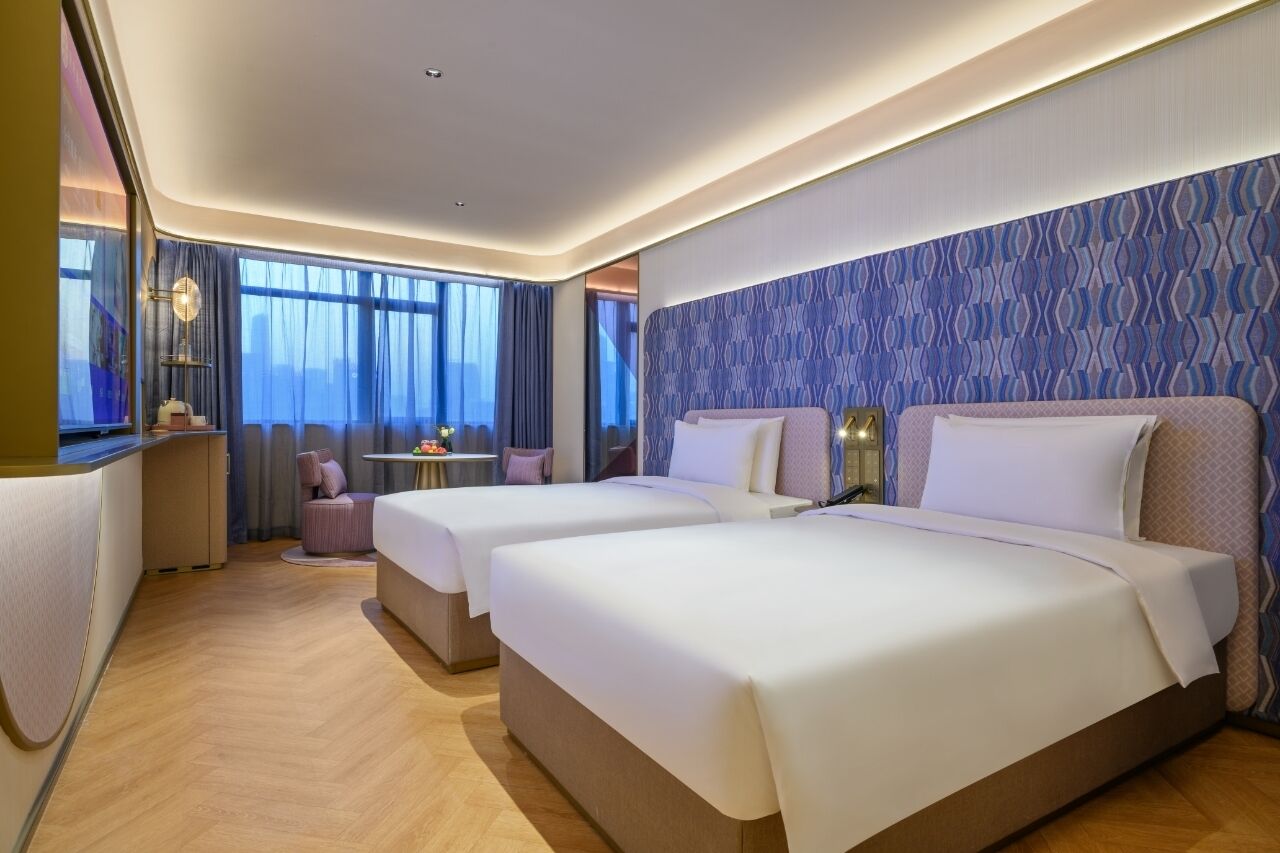 Habitación de hotel con dos camas, una mesita y una silla.