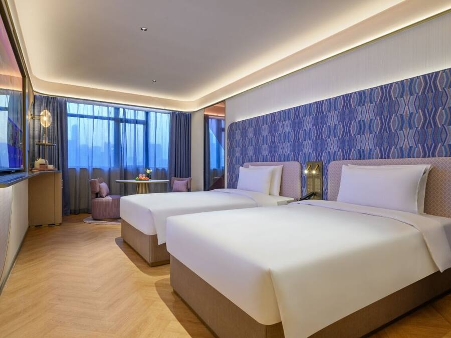 Habitación de hotel con dos camas, una mesita y una silla.