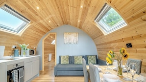 Een gezellig cabin interieur met een keuken, eethoek en een slaaploft met dakramen.
